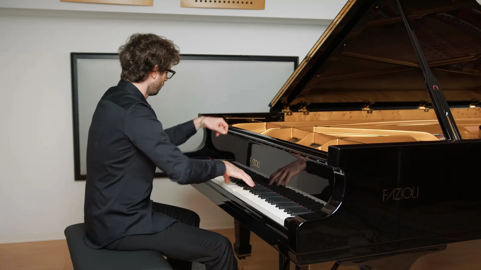 Luca Sacher al pianoforte a coda nella sala, in una lezione