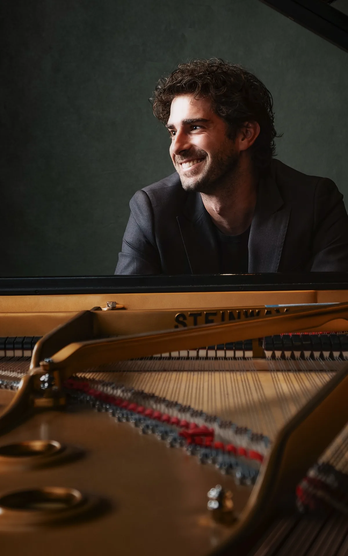 Ritratto di Luca Sacher al pianoforte, in penombra